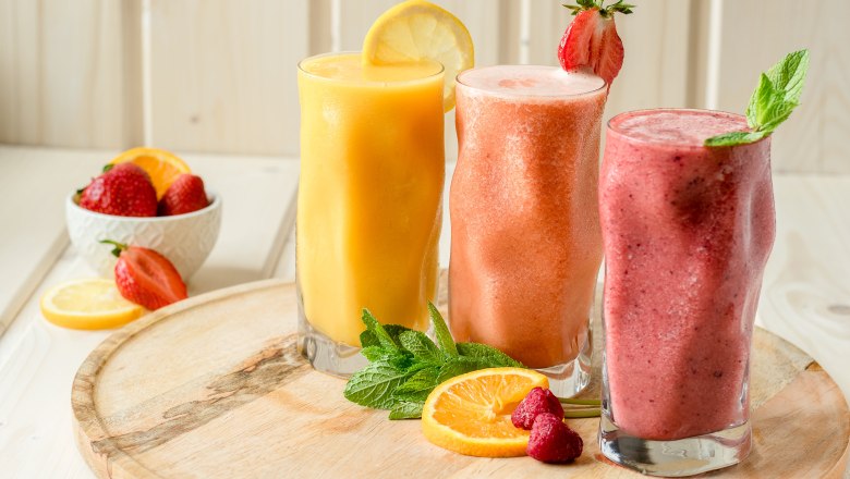 Smoothies, © Koll GmbH Drei bunte Smoothies in Gläsern mit Früchten und Minze dekoriert auf einem Holztablett.