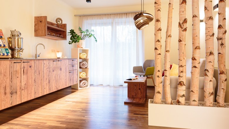 Vitalwelt relaxation room, © Vitalzeit Hotel Weber A cozy relaxation room with wooden furniture, plants and birch trunks as room dividers.
