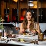 Linsberg Asia_Feine Kulinarik, © Linsberg Asia Frau genießt ein elegantes Abendessen in einem stilvollen Restaurant.