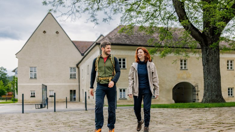 Beim Schloss Katzelsdorf, © Wiener Alpen / Fülöp, Kremsl Ein Mann und eine Frau in Wanderkleidung vor dem Schloss Katzelsdorf