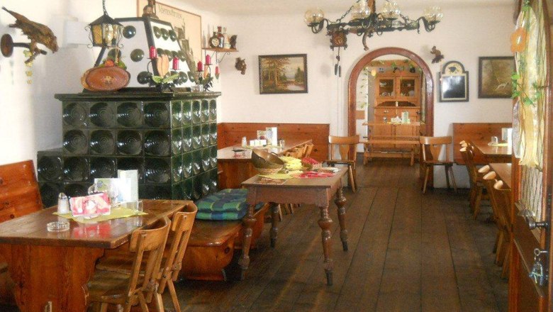 Dorfheuriger Reiterer - Loibernböck, © Thermengemeinden Innenansicht eines traditionellen österreichischen Heurigen mit Holzmöbeln und Kachelofen.