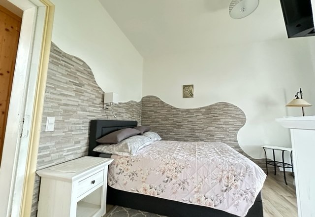 Zimmer Einzelbett, © Schloss Gut Ziegersberg Ein gemütliches Schlafzimmer mit einem Einzelbett, floralem Bettbezug, Nachttisch und dekorativer Wandgestaltung.