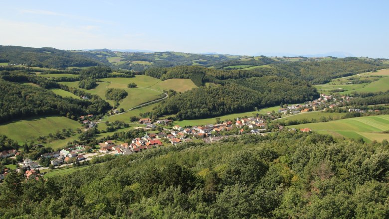 Blick vom "Johann Giefing Aussichtsturm", © Marktgemeinde Schwarzenbach, Helmut Karner Panoramablick auf eine grüne Hügellandschaft mit einem Dorf im Vordergrund, aufgenommen vom Johann Giefing Aussichtsturm.