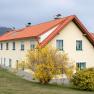 Feriennest Zehetbauer, © heiter-weiter.at/Karl Stangl Gelbes Haus mit rotem Dach und blühendem Strauch im Vordergrund.