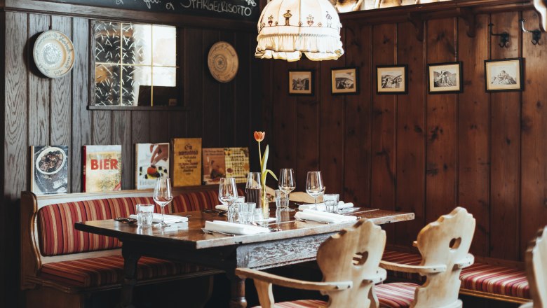 Sooo gut schmeckt die Bucklige Welt, © Niederösterreich Werbung/David Schreiber Gemütliches Restaurant mit Holzwänden, rot gestreiften Sitzbänken und gedecktem Tisch.