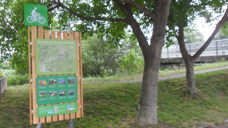 Radstartplatz-Tafel Lanzenkirchen, © ©Wiener Alpen Radstartplatz-Tafel in Lanzenkirchen mit Karte und Informationen, umgeben von Bäumen.