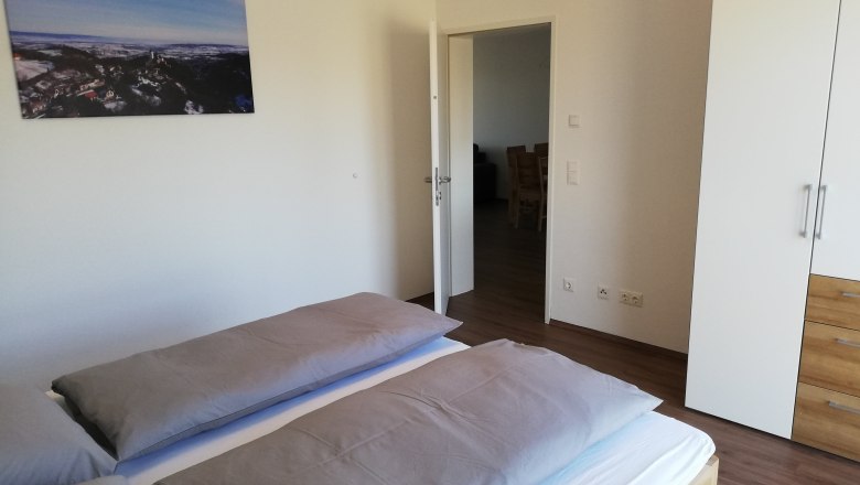 Schlafzimmer, © Peter Hecht Modernes Schlafzimmer mit Doppelbett, weißem Kleiderschrank und Landschaftsbild an der Wand.