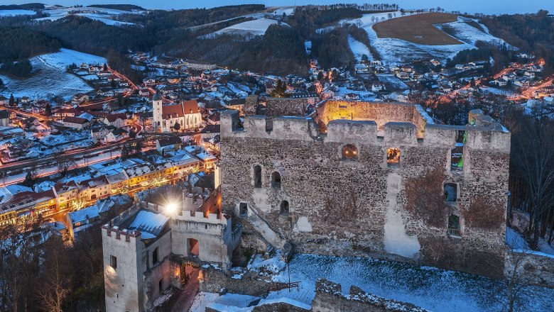 Kirchschlag castle ruins, © Wiener Alpen, Foto: Walter Strobl Kirchschlag castle ruins at dusk with illuminated town in the background.