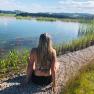 Die Ruhe am Teich genießen..., © Seminarhotel NaturSinne Person sitzt am Ufer eines Teiches mit Blick auf das Wasser und die umliegende Landschaft.