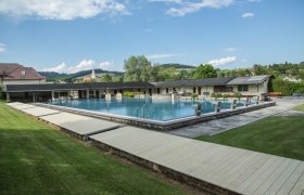Krumbach outdoor pool, © SchwimmbadKrumbach©Marktgemeinde Krumbach, Foto: Franz Riegler Krumbach outdoor pool with swimming pool and diving blocks, surrounded by green landscape and buildings.