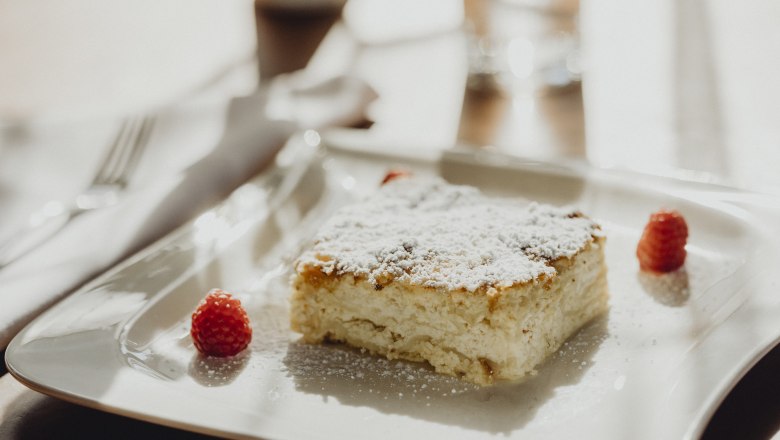 Milchrahmstrudel, © Niederösterreich Werbung/Sophie Menegaldo Ein Stück Milchrahmstrudel mit Puderzucker und Himbeeren auf einem weißen Teller.