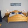 fireworks-in-the-garden, © Besta Betriebs GmbH A bedroom with a wooden double bed, two bedside tables with lamps and a bouquet of flowers on a table.