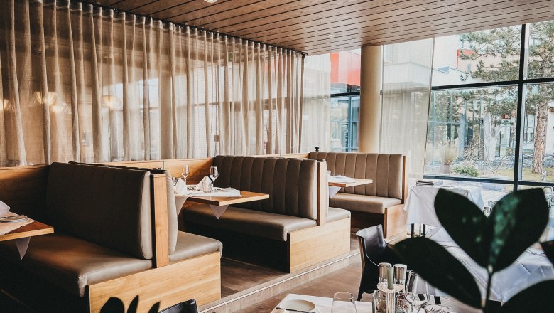 Das Linsberg - Restaurant, © Linsberg Asia Innenansicht eines eleganten Restaurants mit Holzmöbeln und großen Fenstern.