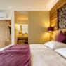 The guest house in the Triad, © Marketing Platzhirsch, Gobauer Modern furnished hotel room with double bed, wooden walls and view into the bathroom.