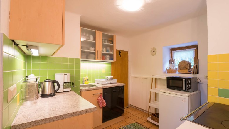 Kitchen, © Wachahof Small kitchen with green tiles, electrical appliances and wooden cupboards.