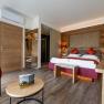 The guest house in the Triad, © Marketing Platzhirsch, Gobauer Modern guest room with double bed, wooden furniture and red accents.