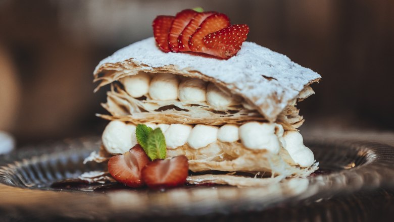 Cremeschnitte, © Niederösterreich Werbung/David Schreiber Eine Cremeschnitte mit Blätterteig, Sahne und Erdbeeren auf einem Teller.