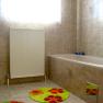 Bathroom, © Anke Spreitzer A bathroom with beige tiled wall, bathtub, radiator and colorful carpets.