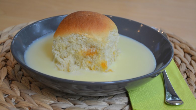 Schlemmen im Turmcafé, © Gemeinde Schwarzenbach Ein schwarzes Teller mit einer Buchtel und Vanillesoße, daneben grüne Serviette mit Gabel.