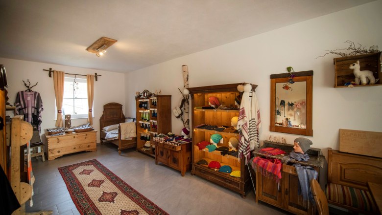 Hofladen - Ederers Alpakahof, © Wiener Alpen, Stefan Knittel Innenansicht eines Hofladens mit Alpakaprodukten, Holzmöbeln und Teppich.