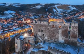 Kirchschlag castle ruins, © Wiener Alpen, Foto: Walter Strobl Kirchschlag castle ruins at dusk with illuminated town in the background.
