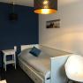 Single room, © Pension zum Spitz A small, modern single room with a bed, a bedside table and a chair.