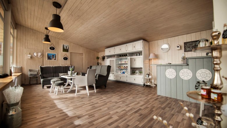 Genusstankstelle - Regionalladen im Ortszentrum, © MG Hochneukirchen-Gschaidt, Stefan Knittel Innenansicht eines gemütlichen Regionalladens mit Holzmöbeln und Dekorationen.