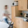 Küche im Feriennest Zehetbauer, © heiter-weiter.at/Karl Stangl Moderne Küche mit Holzmöbeln und einer Person in Bewegung.