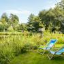 Summer retreat at the Triad, © Wiener Alpen/Martin Fülöp Two blue deckchairs on a meadow on the banks of a pond, surrounded by green vegetation.