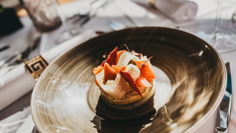 Das Linsberg - Restaurant, © Linsberg Asia Ein kunstvoll angerichtetes Gericht auf einem braunen Teller in einem Restaurant.