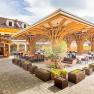 Terrasse, © Christian Kremsl Terrasse mit Holzdach und Tischen, umgeben von Pflanzen.
