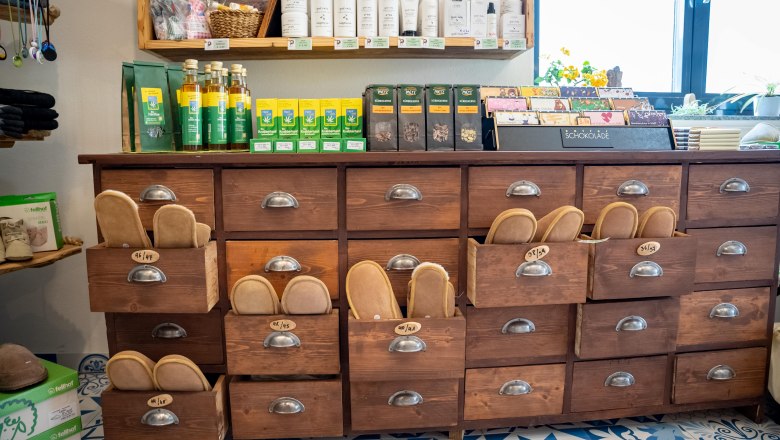 Farm store, © Niederösterreich Werbung / Daniel Groller A shelf in a farm store with wooden drawers containing various products such as chocolate and care products.