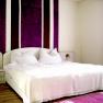 Bedroom 1, © Anke Spreitzer Bedroom with white bed and purple stripes on the wall.