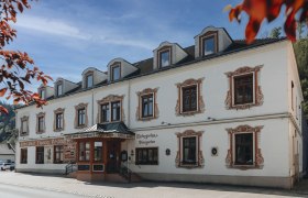 Spezialitäten-Wirtshaus mit Wildtagen oder Fischwochen, © Niederösterreich Werbung/David Schreiber Historisches Gebäude mit dekorativen Fensterrahmen und Schildern für Hotel und Restaurant.