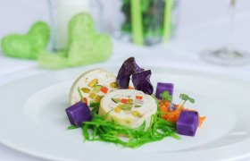 Haubenküche im Gesundheitsresort Königsberg, © Gesundheitsresort Königsberg Kunstvoll angerichtete Maishendlroulade, lila Kartoffelwürfeln und grüner Garnitur auf einem weißen Teller.
