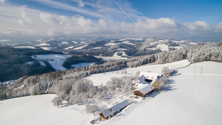 The Wachahof in winter, © Wachahof Snowy landscape with farm and hills in the background.
