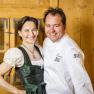 the innkeepers, © Lukas Kirchgasser A man in a chef's jacket and a woman in traditional costume smile at the camera.