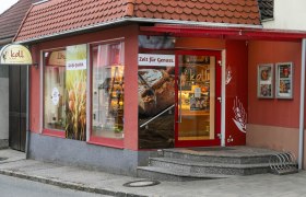 Fachgeschäft mit Café in Wiesmath, © Koll GmbH Eingang der Bäckerei mit Café in Wiesmath, mit roten Wänden und Schildern.