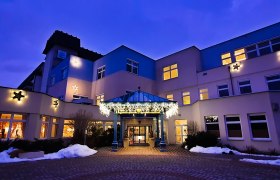 Gesundheitsresort Königsberg, © Gesundheitsresort KÖNIGSBERG, Bad Schönau Beleuchtetes Gebäude bei Dämmerung mit weihnachtlicher Dekoration.