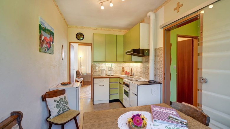 Kitchen, © Wachahof Kitchen with green cupboards, dining table with flowers, door to the living room.