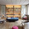 Bibliothek, © Seminarhotel NaturSinne Gemütliche Bibliothek mit großen, beleuchteten Bücherregal, Sesseln und einer Person, die liest.