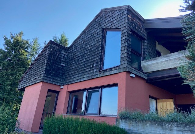 Modernes Haus mit Holzschindeln und gro&szlig;en Fenstern.