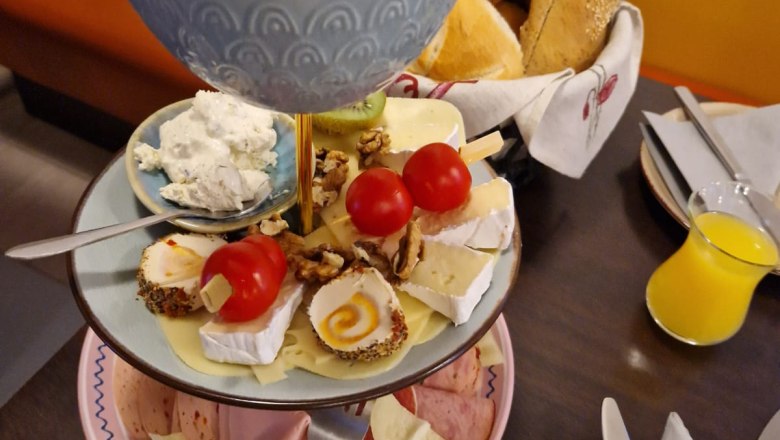Frühstücksetagere mit Aufschnitt, Käse, Brötchen und Butter im Café.