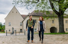 Ein Mann und eine Frau in Wanderkleidung vor dem Schloss Katzelsdorf