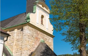 Pfarrkirche Thernberg mit Turm und Baum im Vordergrund.