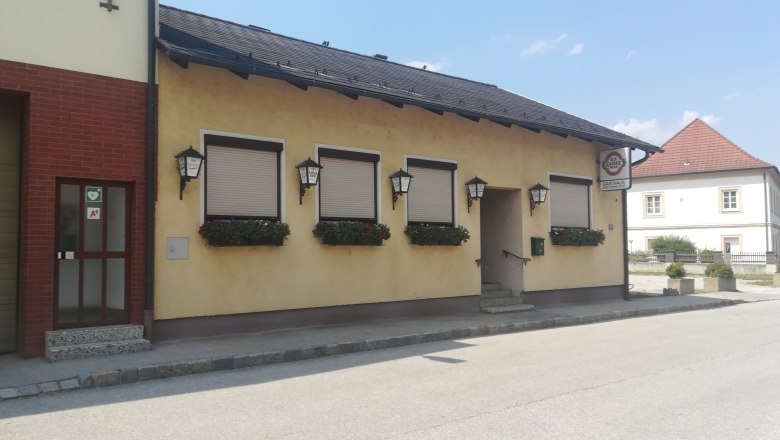 Exterior view of a yellow inn with closed shutters and flower boxes.