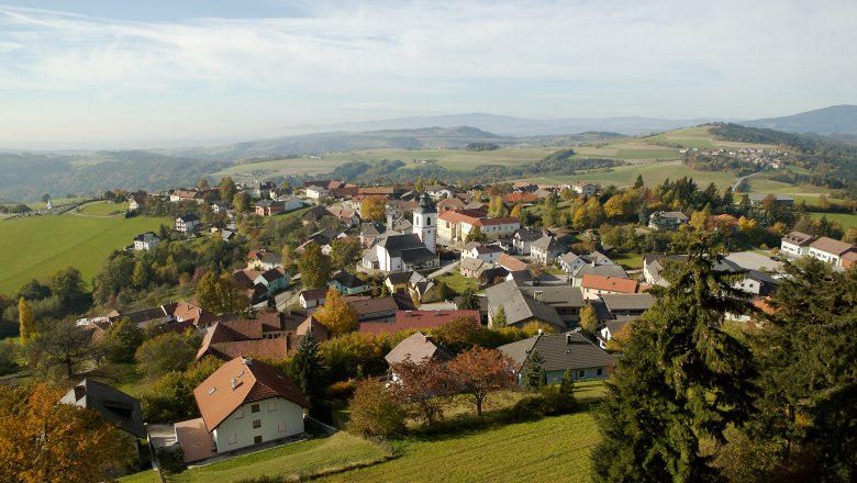 Luftaufnahme von Hochneukirchen-Gschaidt mit Häusern, Kirche und grüner Landschaft.