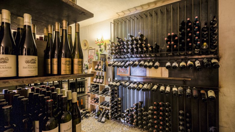 Ein Weinkeller mit Regalen voller Weinflaschen, die ordentlich gestapelt sind.