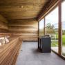 Moderne Sauna mit Holzverkleidung und großer Glasfront mit Blick ins Grüne.