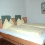 Hotelzimmer mit Doppelbett, gelber Bettwäsche und Wandbild.